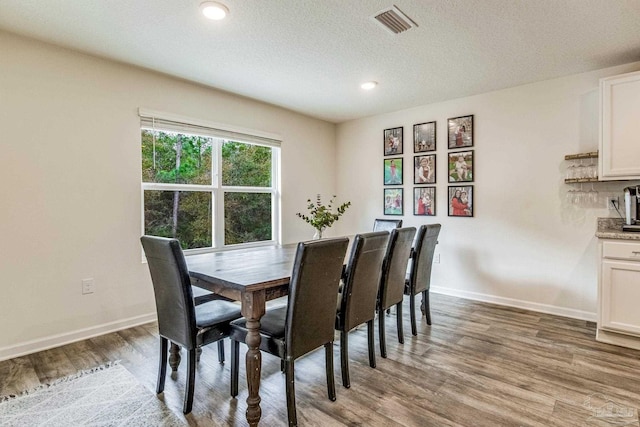 dining area with light hardwood / wood-style floors and a textured ceiling