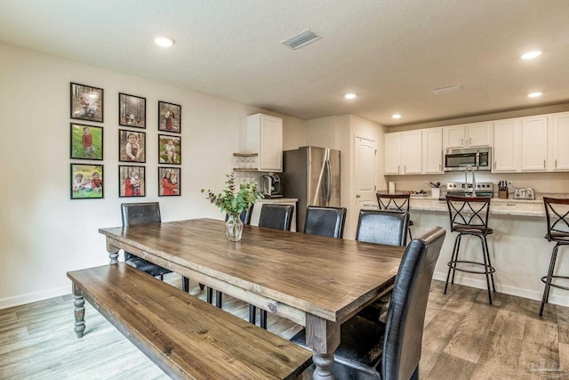 dining room featuring light hardwood / wood-style floors and a textured ceiling