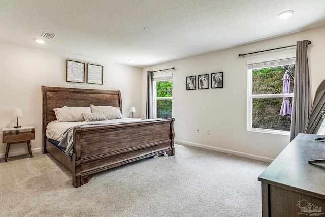 bedroom with light carpet and a textured ceiling