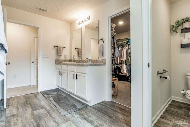 bathroom featuring wood-type flooring, vanity, and a textured ceiling