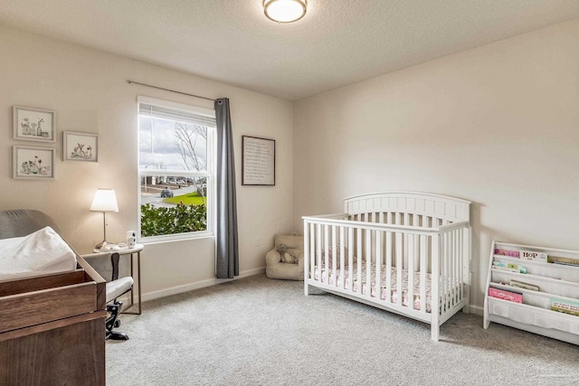 bedroom with a nursery area, light colored carpet, and a textured ceiling