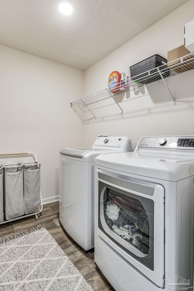 washroom with washing machine and clothes dryer, wood-type flooring, and a textured ceiling