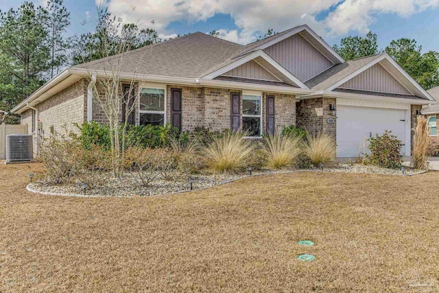 view of front of home with a garage, a front lawn, and central air condition unit