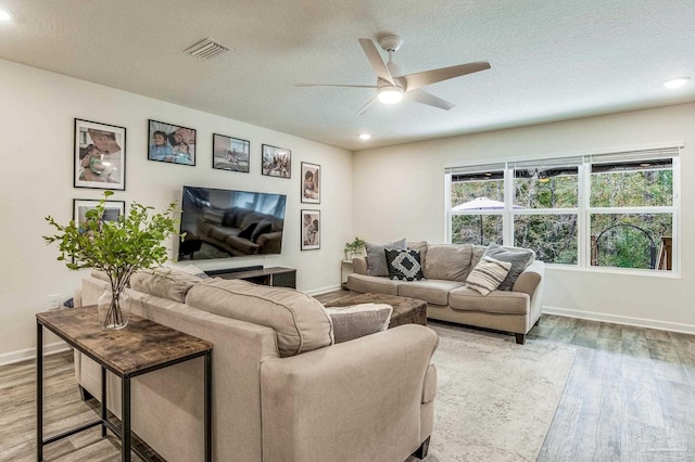 living room with hardwood / wood-style flooring, ceiling fan, and a textured ceiling