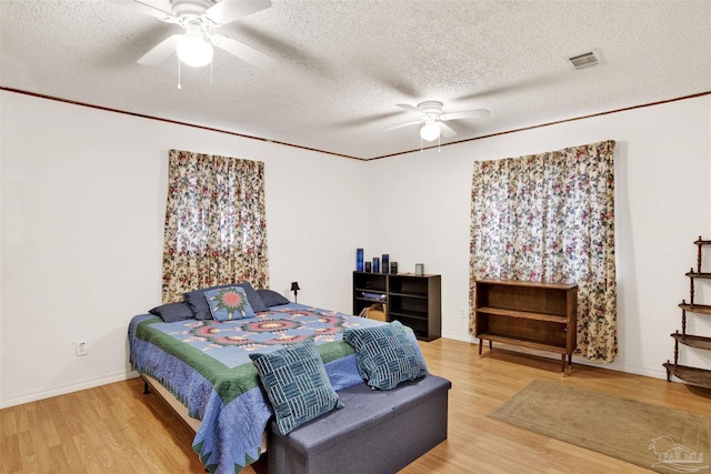 bedroom with ceiling fan, hardwood / wood-style floors, and a textured ceiling