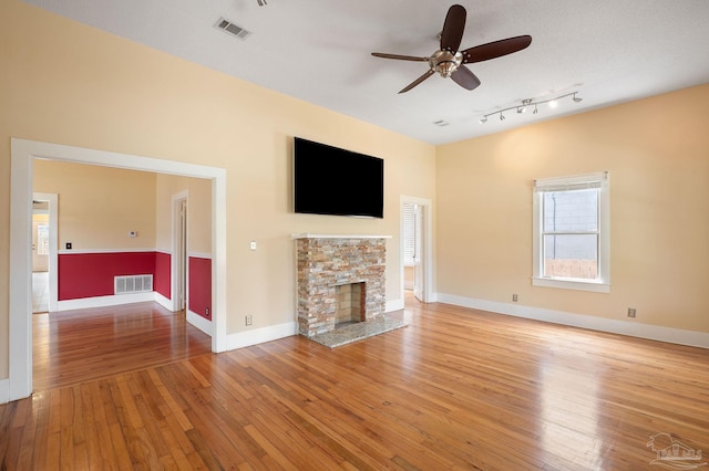 unfurnished living room with a fireplace, ceiling fan, and light wood-type flooring