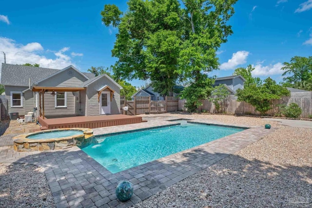 view of pool featuring an in ground hot tub, pool water feature, a wooden deck, and a patio area