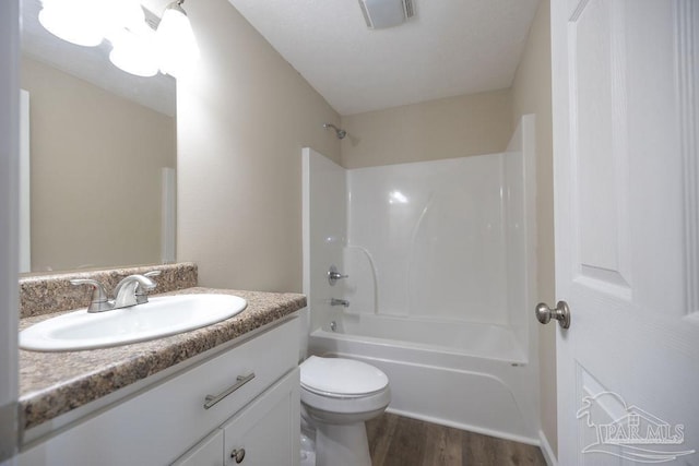 full bathroom with hardwood / wood-style flooring, vanity, shower / washtub combination, and toilet