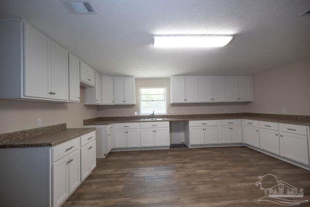 kitchen featuring sink, a textured ceiling, dark hardwood / wood-style flooring, and white cabinetry