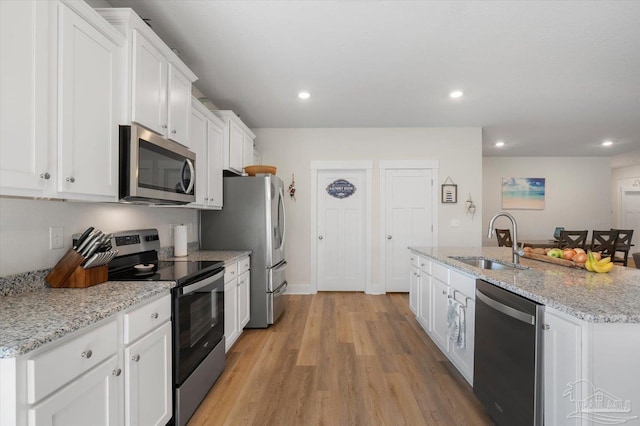 kitchen with light wood-type flooring, sink, white cabinets, stainless steel appliances, and light stone countertops