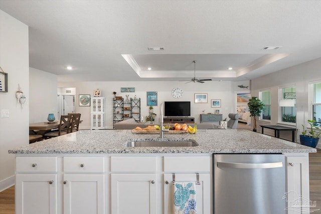 kitchen with dishwasher, a tray ceiling, hardwood / wood-style floors, and white cabinetry