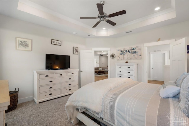 bedroom featuring a raised ceiling, ceiling fan, and light colored carpet