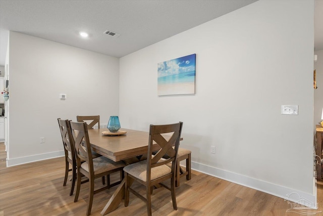 dining space with light wood-type flooring and a textured ceiling