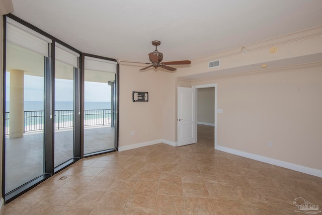 tiled spare room featuring a water view, ceiling fan, and expansive windows