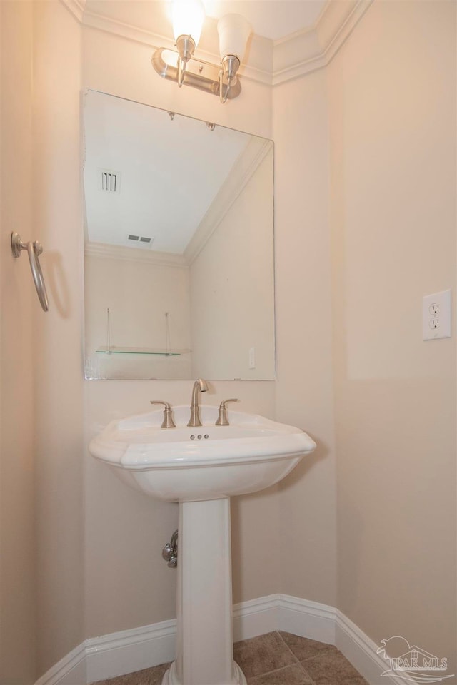 bathroom with tile patterned flooring, crown molding, and sink