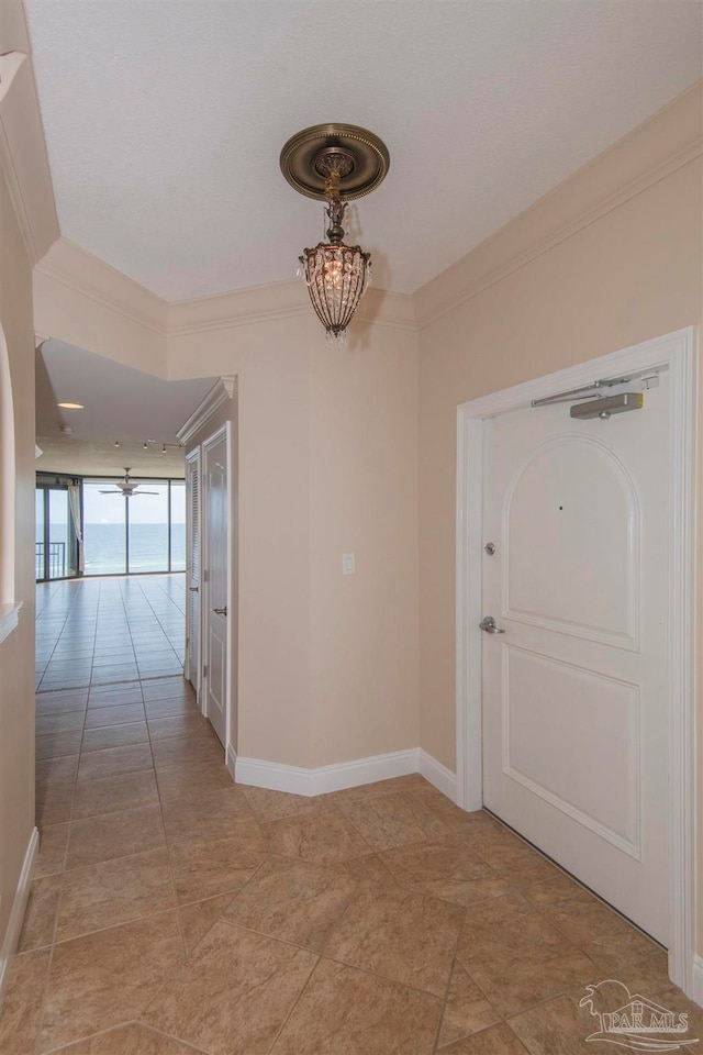 hallway with crown molding, a notable chandelier, and light tile patterned floors