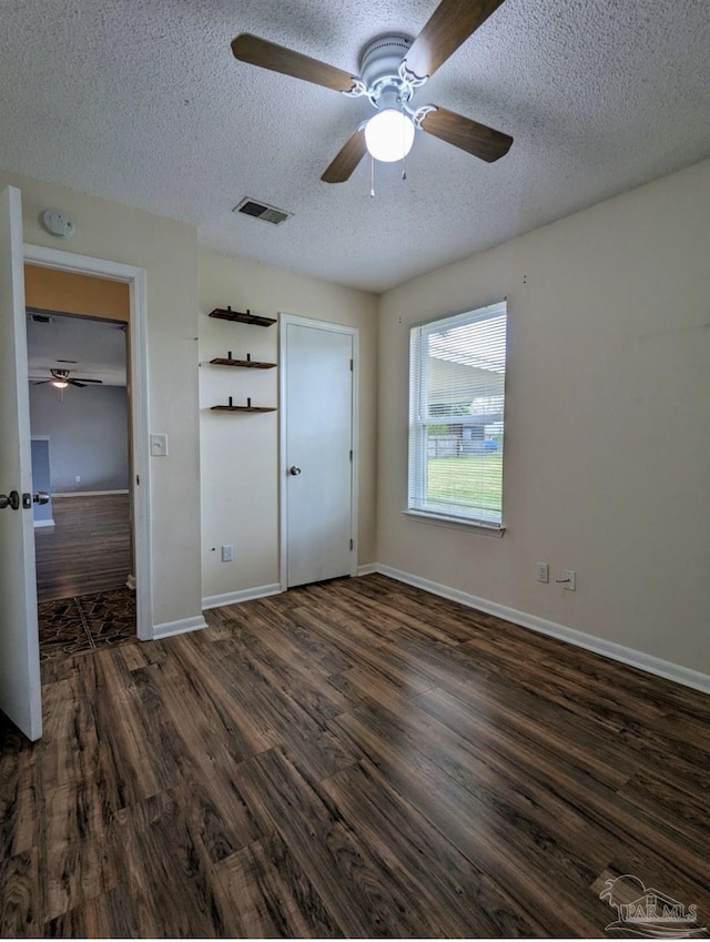 unfurnished bedroom featuring ceiling fan, dark hardwood / wood-style floors, and a textured ceiling