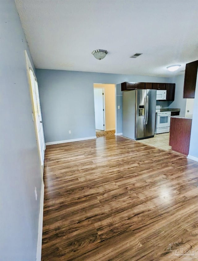 kitchen with white appliances, dark brown cabinetry, and light wood-type flooring