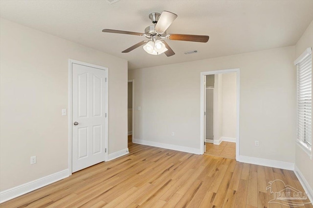 8868 Sanderling Ln, Navarre, FL 32566 - unfurnished bedroom featuring light wood-style floors, baseboards, a ceiling fan, and a walk in closet