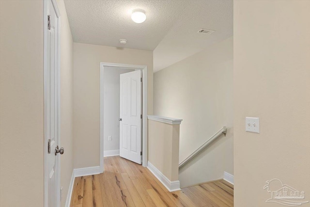 8868 Sanderling Ln, Navarre, FL 32566 - corridor with an upstairs landing, light wood finished floors, a textured ceiling, and baseboards