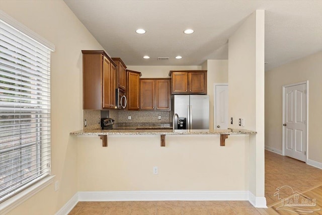 8868 Sanderling Ln, Navarre, FL 32566 - kitchen featuring stainless steel appliances, light stone counters, a peninsula, backsplash, and a kitchen bar
