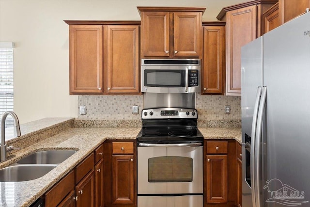 8868 Sanderling Ln, Navarre, FL 32566 - kitchen with stainless steel appliances, a sink, tasteful backsplash, and brown cabinetry
