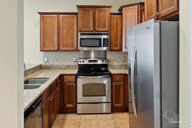 8868 Sanderling Ln, Navarre, FL 32566 - kitchen featuring appliances with stainless steel finishes, light stone counters, a sink, decorative backsplash, and light tile patterned flooring