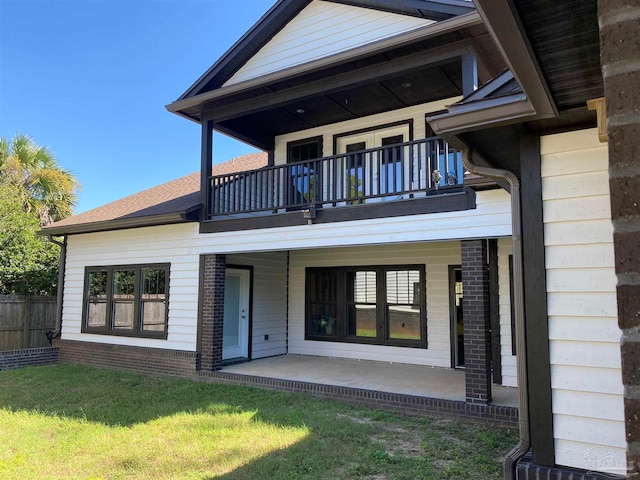 back of property featuring a lawn, a balcony, and a patio area