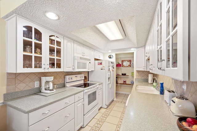 1650 Bulevar Menor, Pensacola Beach, FL 32561 - kitchen with decorative backsplash, a textured ceiling, a sink, white cabinets, and white appliances