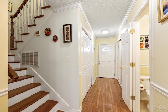 1650 Bulevar Menor, Pensacola Beach, FL 32561 - corridor with light wood finished floors, a textured ceiling, stairs, visible vents, and ornamental molding