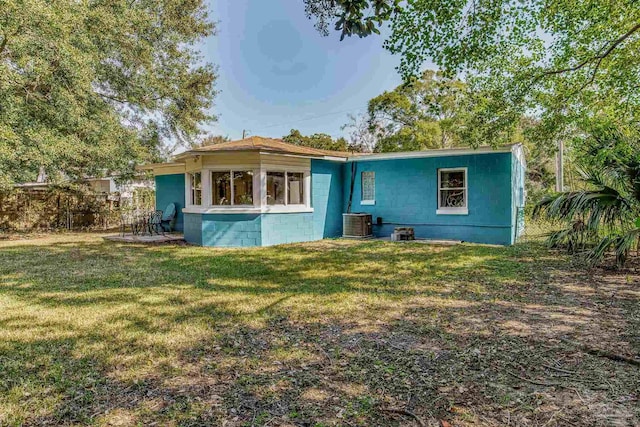 back of property featuring central AC and a lawn