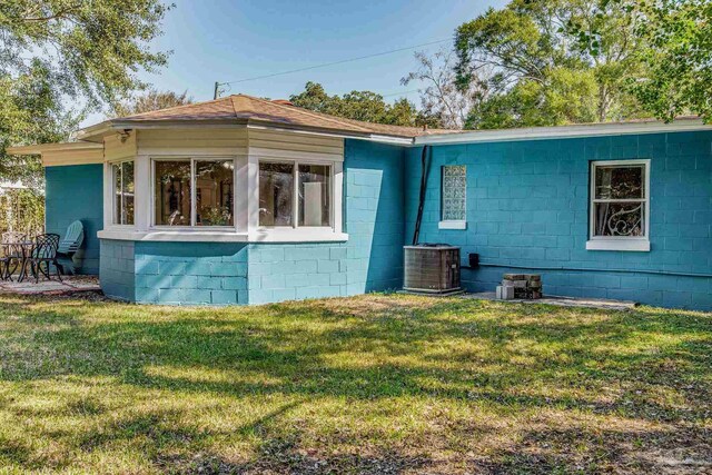 rear view of house featuring a lawn and central AC unit