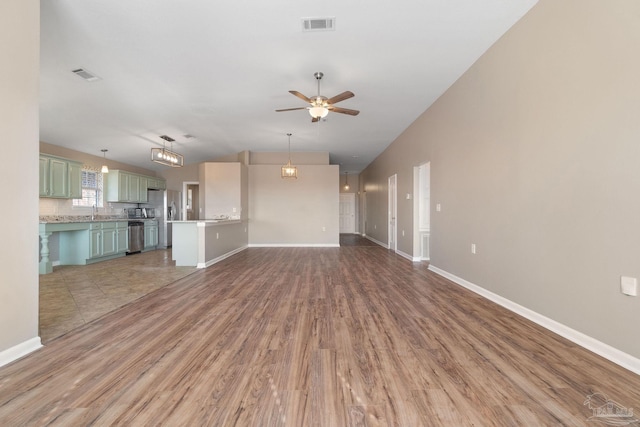 unfurnished living room featuring ceiling fan, sink, and hardwood / wood-style flooring