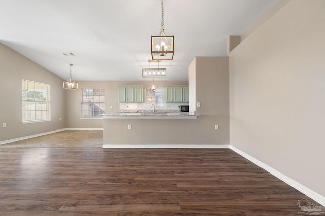 unfurnished living room with dark hardwood / wood-style floors, sink, and vaulted ceiling