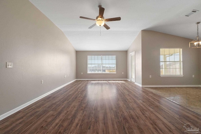 empty room featuring ceiling fan with notable chandelier, dark wood-type flooring, and lofted ceiling