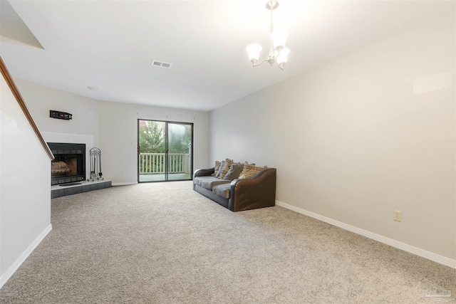 carpeted living room featuring a notable chandelier and a tiled fireplace