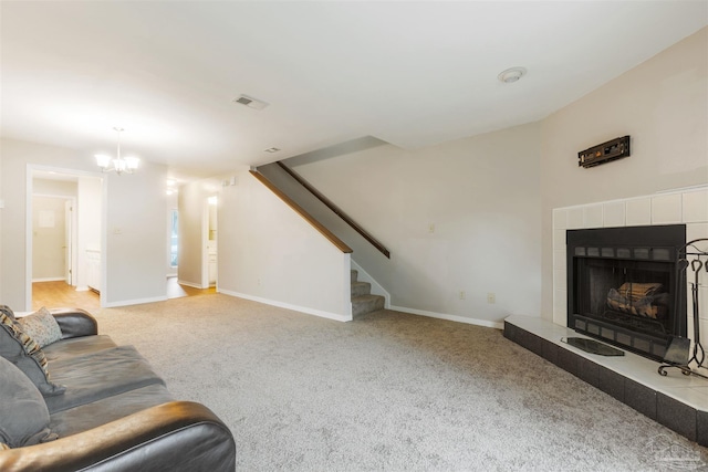 carpeted living room featuring an inviting chandelier and a tiled fireplace