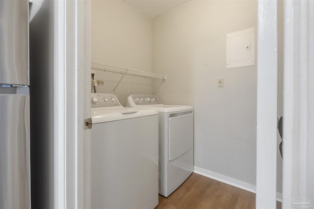 laundry room featuring independent washer and dryer, electric panel, and light hardwood / wood-style flooring