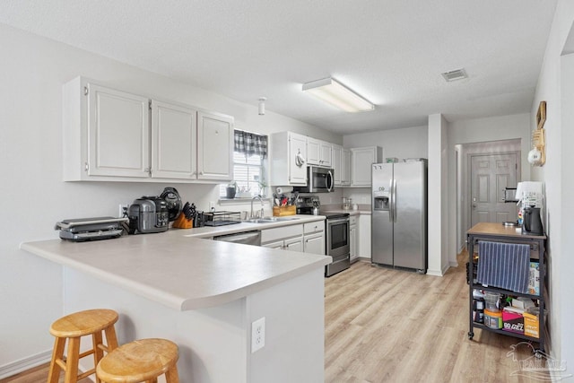 kitchen featuring appliances with stainless steel finishes, kitchen peninsula, white cabinets, and a breakfast bar