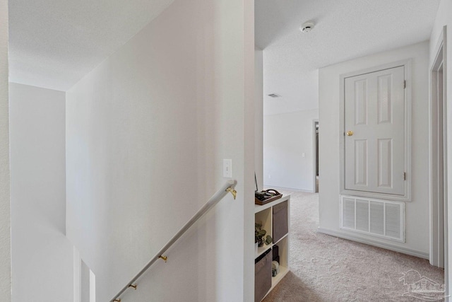 hall with carpet flooring and a textured ceiling