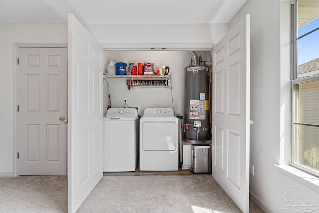 clothes washing area with light colored carpet, washer and clothes dryer, and gas water heater