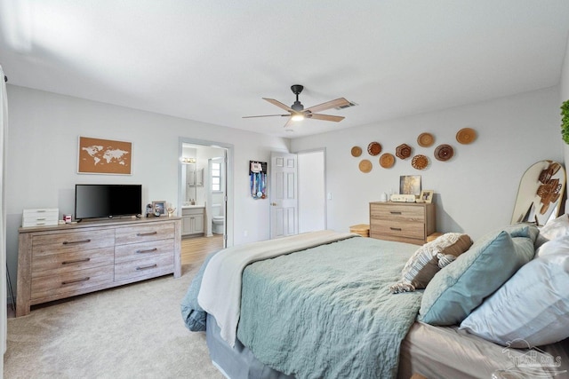 bedroom with light carpet, ensuite bathroom, and ceiling fan