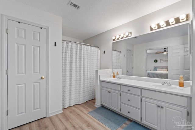 bathroom featuring vanity, hardwood / wood-style floors, a textured ceiling, and ceiling fan