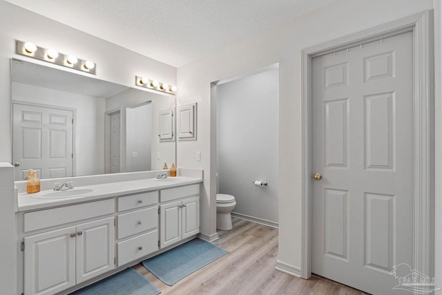 bathroom featuring vanity, hardwood / wood-style floors, a textured ceiling, and toilet