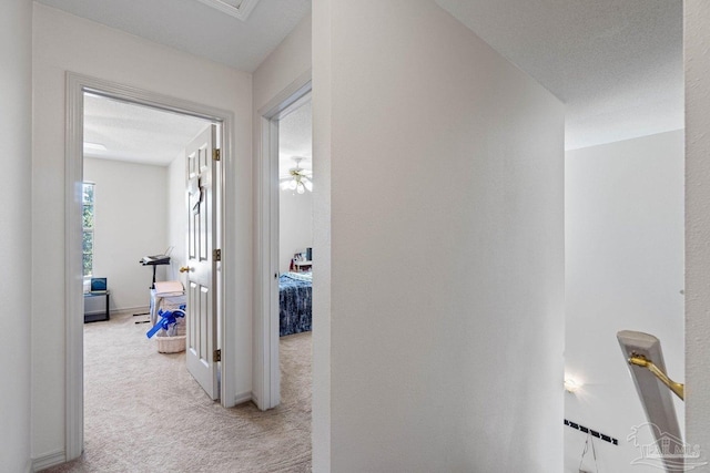 corridor featuring light carpet and a textured ceiling