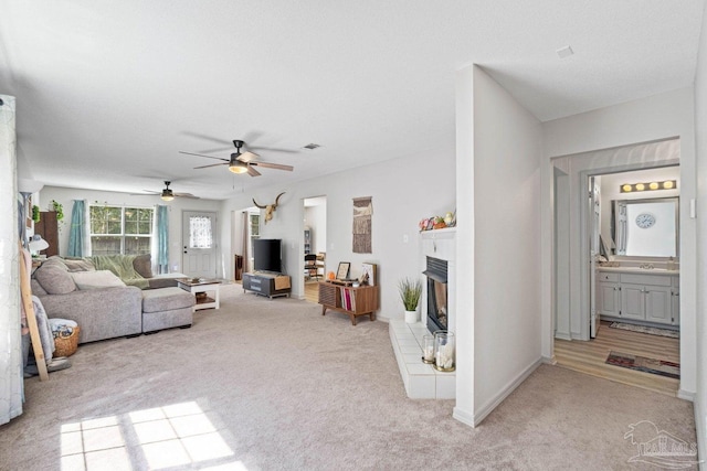 carpeted living room featuring a brick fireplace and ceiling fan