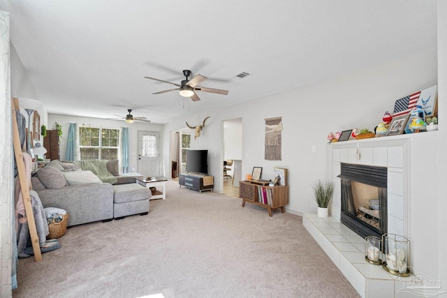 carpeted living room with ceiling fan and a tile fireplace