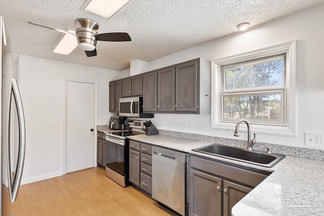 kitchen with a sink, a textured ceiling, appliances with stainless steel finishes, light countertops, and ceiling fan