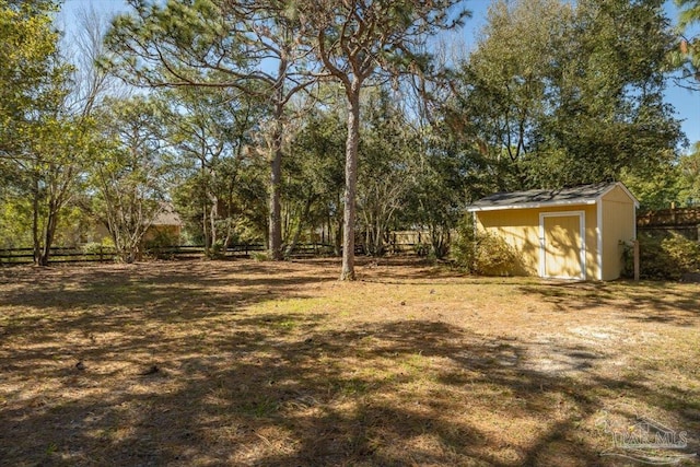 view of yard featuring a storage shed, an outdoor structure, and fence