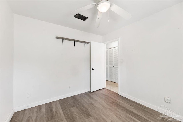 unfurnished room featuring baseboards, wood finished floors, and a ceiling fan